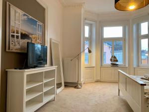 吕贝克Villa Wakenitz的一间客厅,客厅的白色橱柜上配有电视