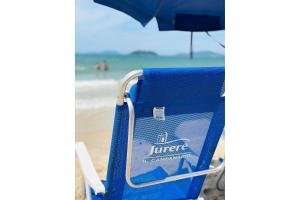 弗洛里亚诺波利斯Cobertura luxuosa dentro de Resort - Direto com proprietário - ILCMASTER的海滩上带遮阳伞的蓝色沙滩椅
