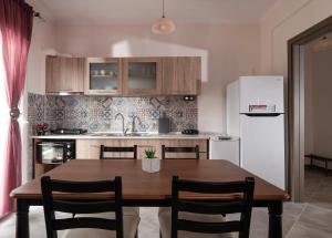普萨克迪亚mansion luxury apartment的厨房配有木桌和白色冰箱。