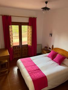 昆卡Hostal Ciudad Encantada的一间卧室配有大床和红色窗帘