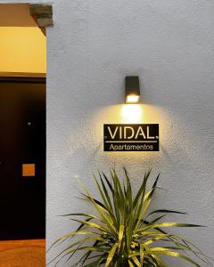 卡莫纳VIDAL APARTAMENTOS con parking privado.的挂在墙上的挂有植物的警戒装置的标志