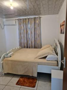 马罗尼河畔圣洛朗CHEZ VERVEINE的白色房间的床,床边有窗帘和床