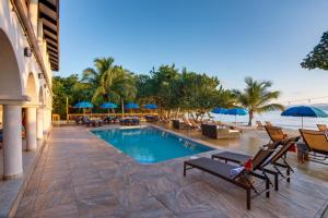 珀拉什奇亚Mariposa Belize Beach Resort的度假村的游泳池,配有椅子和遮阳伞