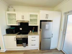 圣弗朗西斯湾Modern 3 Bedroom Townhouse in St Francis Bay的厨房配有白色橱柜和不锈钢冰箱