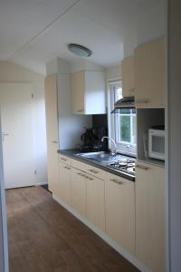 登堡Vakantiepark Dennenoord的厨房配有白色橱柜、水槽和微波炉