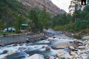 本贾尔LivingStone Backwater Resort Tirthan Valley的一条有岩石和交通灯的河流