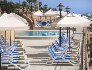 圣朱利安斯马耳他科林西亚海滩海滨度假酒店的一组椅子和遮阳伞,位于游泳池旁