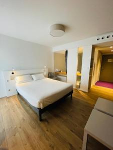 昂代圣地亚​​哥餐厅酒店的卧室配有一张白色的大床,铺有木地板