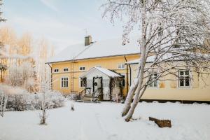 KauhajokiSalaisen Puutarhan Majatalo的一座大黄色房子,地面上积雪