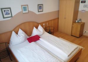 克洛斯特新堡阿尔特磨坊膳食公寓酒店的一张白色的大床,上面有红色枕头