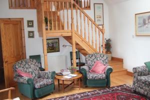 邓凯尔德Tomnagairn Cottage的一间带两把椅子和楼梯的客厅