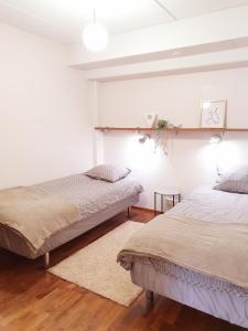 萨斯塔马拉Ellivuori Resort Hehku的配有白色墙壁和木地板的客房内的两张床