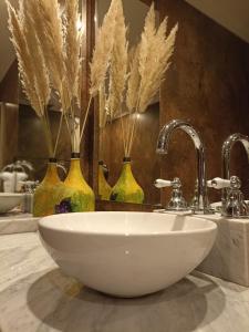 乌斯帕亚塔Uspallata Suites的浴室设有水槽和3个带羽毛的花瓶