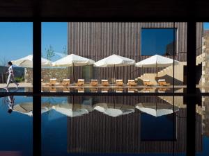 阿马兰特Monverde - Wine Experience Hotel - by Unlock Hotels的一个人在带遮阳伞和桌子的游泳池边散步