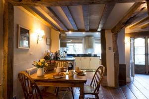 萨弗伦沃尔登Miller Cottage a luxury 1550's cottage in the Historic centre of Saffron Walden的一间带木桌和椅子的厨房以及一间用餐室