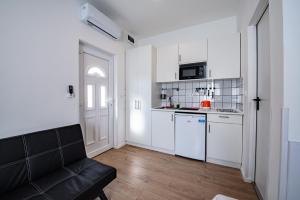 布达佩斯Chesscom Apartments的厨房配有白色橱柜和黑色沙发