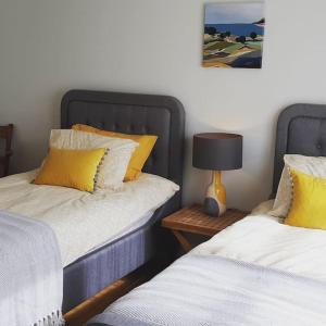 布莱尔高里Pinewood Cotage - Country Walks and Relaxation的一间卧室设有两张床和一张桌子上的台灯。