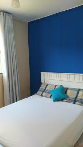 卡皮托利乌Cantinho Xodó的蓝色的卧室设有白色的床和蓝色的墙壁