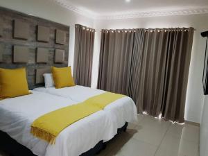 克拉伦斯8sIndoor indoor pool4 bedroom villaGreat view and backup power的卧室内的两张床和黄色枕头