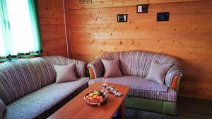 库伦瓦库夫Wooden House "Una"的客厅设有两张沙发和一张带一碗水果的桌子