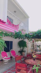 圣玛尔塔Casa Hospedaje Villaluz- a 5 minutos de la Playa的一个带粉红色桌椅的庭院和一个阳台