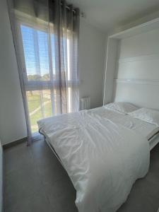 勒格罗-迪鲁瓦Les Pieds dans le Sable的卧室设有一张白色的床和大窗户