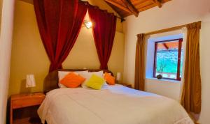 奥兰太坦波Casa de Ollanta ByB的一间卧室配有一张带红色窗帘的床和一扇窗户