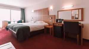 布兰肯贝赫Hotel Riant-Séjour by WP Hotels的酒店客房带一张床、一张书桌和一面镜子