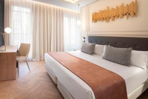 马德里戈雅加泰罗尼亚酒店的卧室配有一张白色大床和一张书桌