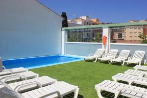 罗列特海岸Hotel Armonía的一个带白色椅子的庭院和一个游泳池