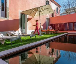 辛特拉Rosegarden House - by Unlock Hotels的一个人在带雨伞的游泳池边散步