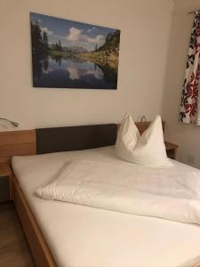 列兴Panoramablick Tscheltsch的一张铺有白色床单的床和一张墙上的照片