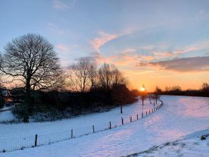 AppelternAtelier Onder de Notenboom的雪覆盖的田野,围栏和日落