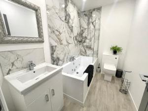 布莱克浦Osborne luxury hot tub and jacuzzi suites的白色的浴室设有水槽和卫生间。