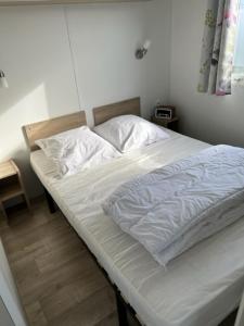米德尔克尔克Luxe stacaravan的卧室内的一张带白色床单和枕头的床