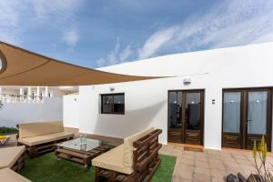 卡门港villa del mar puerto del carmen的白色的房子,设有配有桌子和长凳的庭院