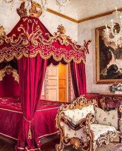 那不勒斯Palazzo Doria Napoli的一间卧室配有一张带红色窗帘的床和一把椅子