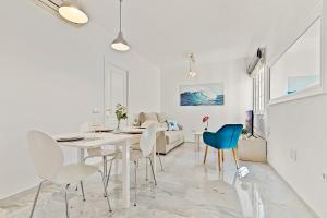 福恩吉罗拉Apartamentos a 1 minuto de la playa的白色的用餐室配有白色的桌椅