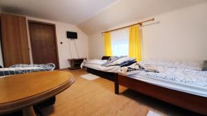 波兰尼卡-兹德鲁伊Agroturystyka u Joli的客房设有两张床、一张桌子和一扇窗户。