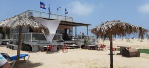圣玛丽亚AH Xamedu Sal Hostel的海滩上的一座建筑,配有椅子和遮阳伞