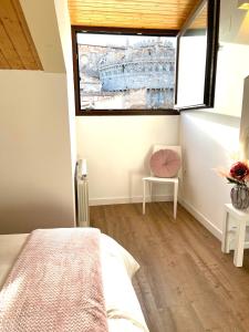 阿维拉Estrada Suites的一间卧室设有一张床、一个窗口和一把椅子
