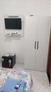 古里里Suítes Privativas em Guriri的配有电视、床和橱柜的房间