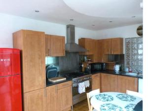 泰恩河畔纽卡斯尔Lovely 2 bed flat in the VERY CENTRE of Newcastle的厨房配有木制橱柜、桌子和红色冰箱。