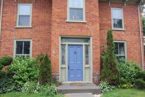 惠灵顿County Cove - Bloomfield Suite的前面有蓝色门的砖砌建筑