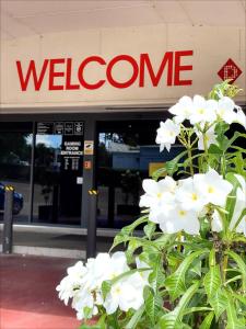 布里斯班Inala Hotel的带有迎宾标志和白色花的建筑