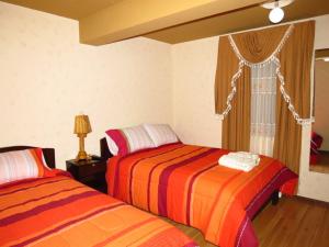 乌尤尼朱马利酒店的一间卧室设有两张床和窗户。