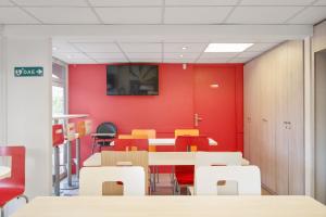 德希内斯·尚皮埃普瑞米尔里昂东布隆厄科尔斯博经典酒店的一间拥有红色墙壁和桌椅的用餐室
