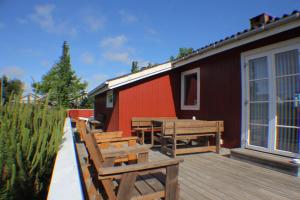 布拉万德The Little Red Cabin Near Blåvand!的一个带长椅和桌子的甲板和一座建筑