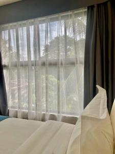 TanauanBravo Tanauan Hotel的一间卧室配有床和白色窗帘的窗户
