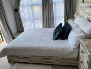 比勒陀利亚Lime Court two的卧室配有带枕头的木床和窗户。